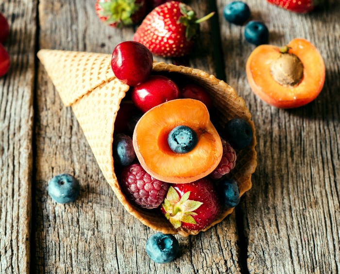 Waffle cone filled with fresh berries and apricot halves