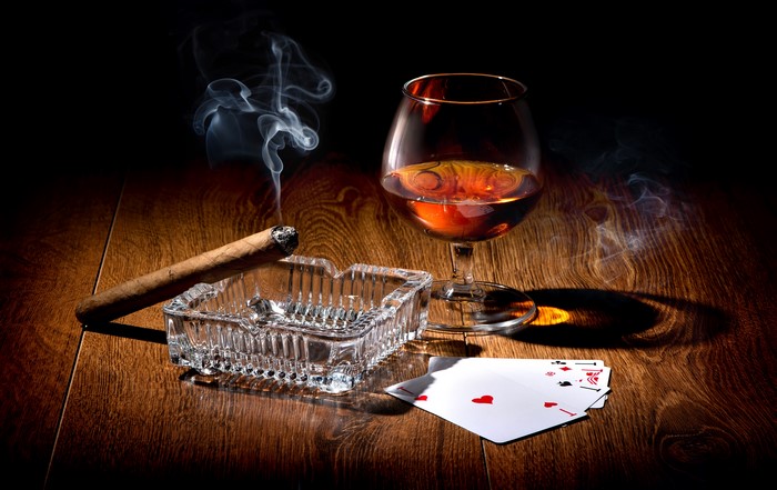 Cigar, Brandy, and Playing Cards on Wooden Table