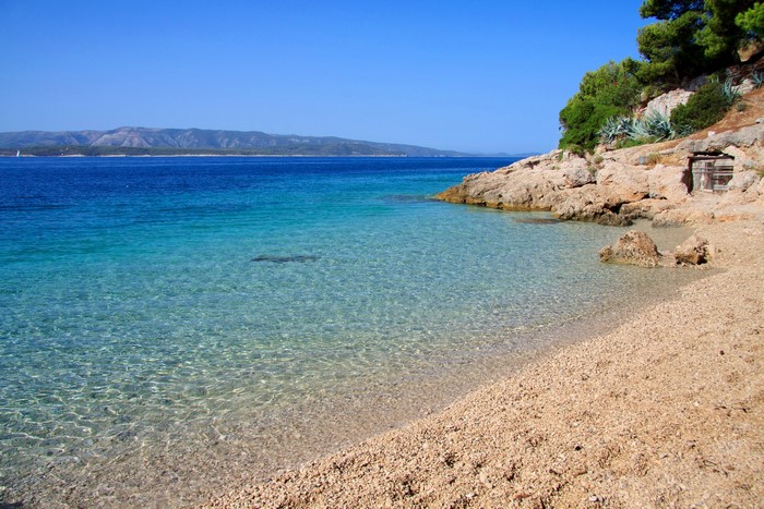 Pebble beach with clear turquoise water and rocky coast