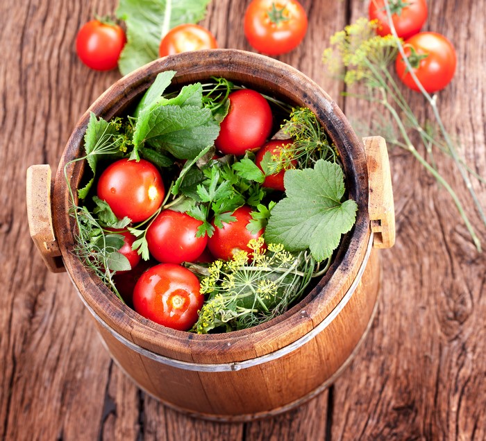 Tomatoes and herbs in a wooden barrel