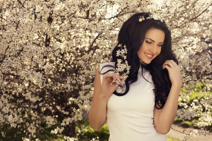 Brunette girl with flowers in flowering trees