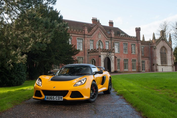 Yellow Lotus Exige Sport Coupe in front of a brick building