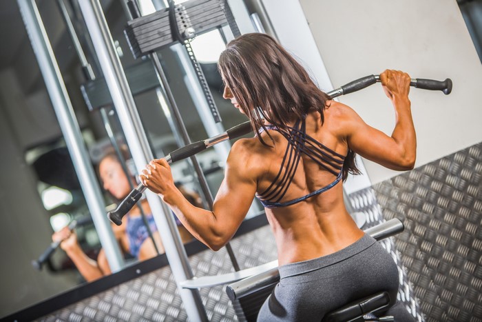Woman performing lat pulldown exercise in gym