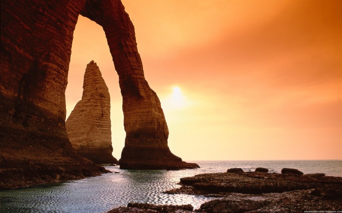 Arch rock formation over the ocean at sunset