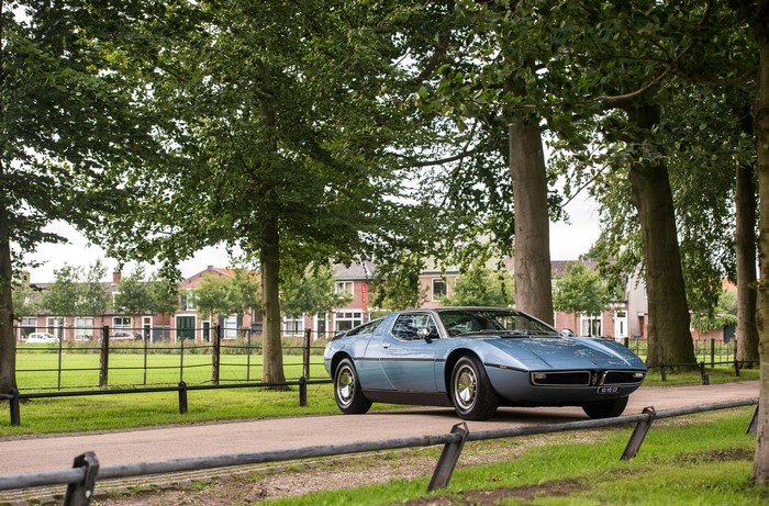 Blue Maserati Bora AM117 parked on a tree-lined road