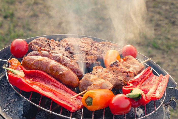 Meat products, sausages, and vegetables on a grill