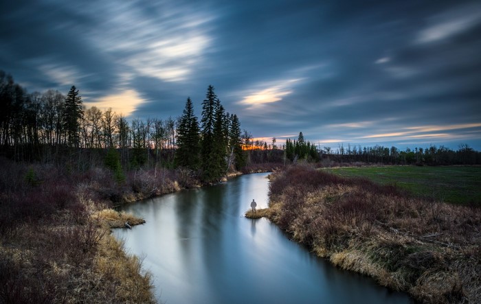 Man fishing by river at dusk in Sturgeon County, Alberta