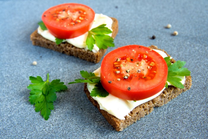 Two open-faced sandwiches with tomato and parsley