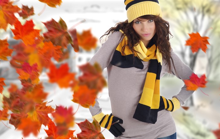Woman in autumn hat and scarf with falling leaves