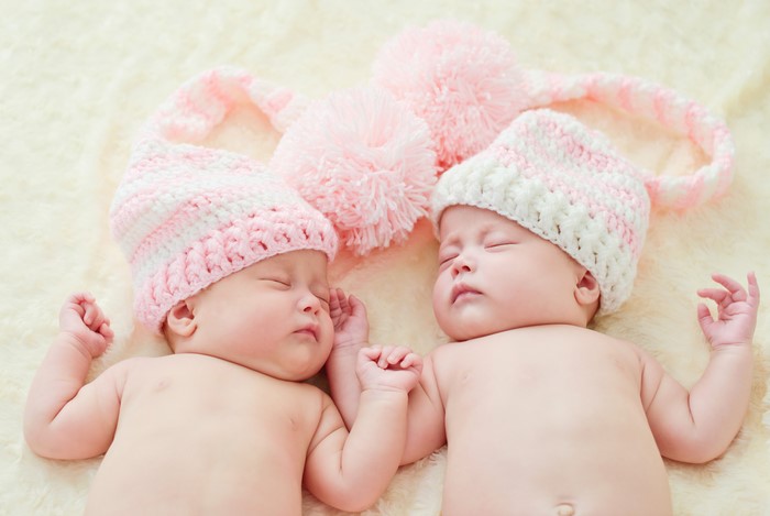 Two infants sleeping in winter hats