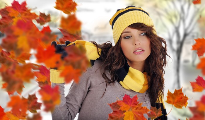 Woman in autumn hat and scarf with falling leaves
