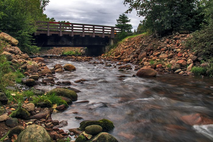 Wooden bridge over a rocky river in Quebec, Canada