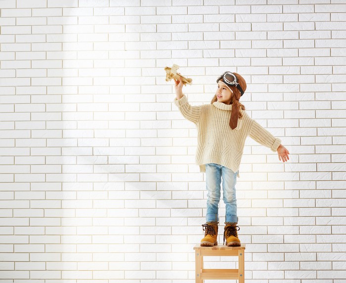 Girl in pilot hat holding toy airplane