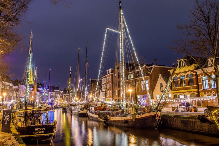 Boats decorated with lights on a canal at night in Groningen