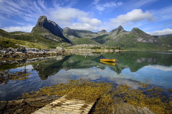 Yellow boat on a calm lake with mountains in Norway