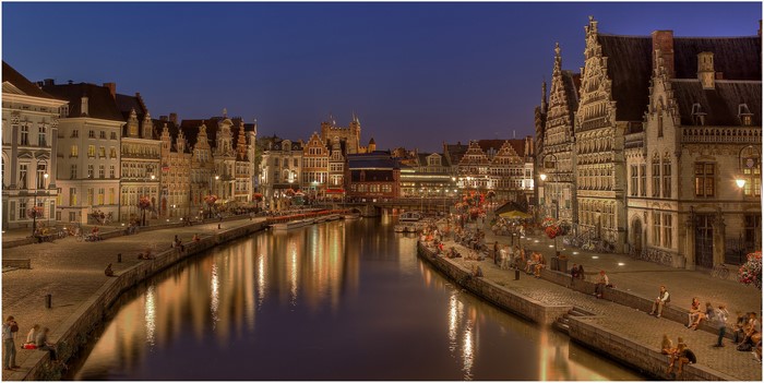 Ghent canal at night with historic buildings and people
