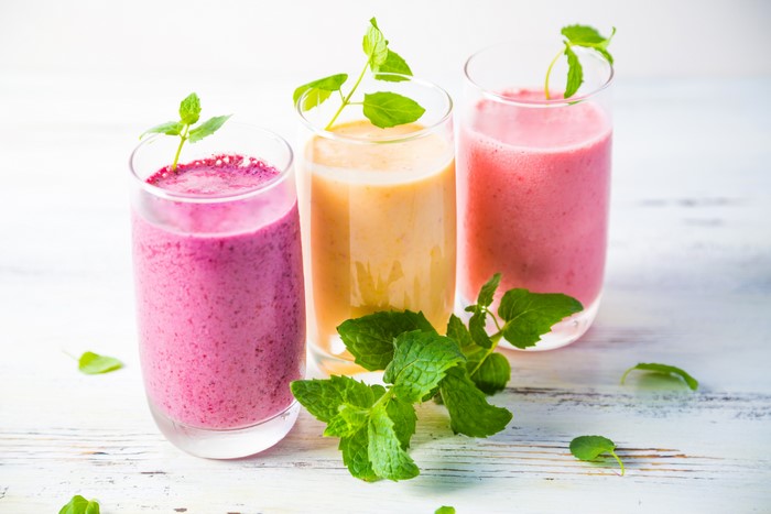 Three colorful smoothies in highball glasses with mint leaves