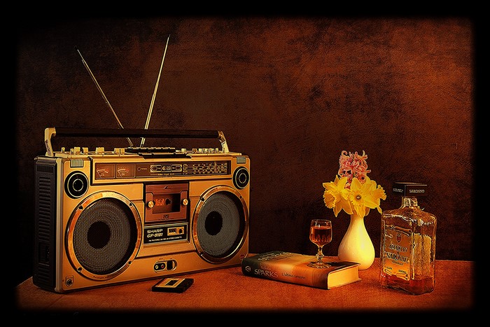 Boombox, book, flowers, and liquor bottle still life