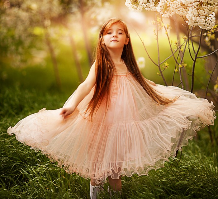 Young girl in a pink dress in a garden
