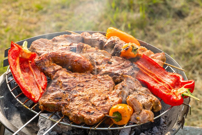 Meat products and bell peppers on a grill