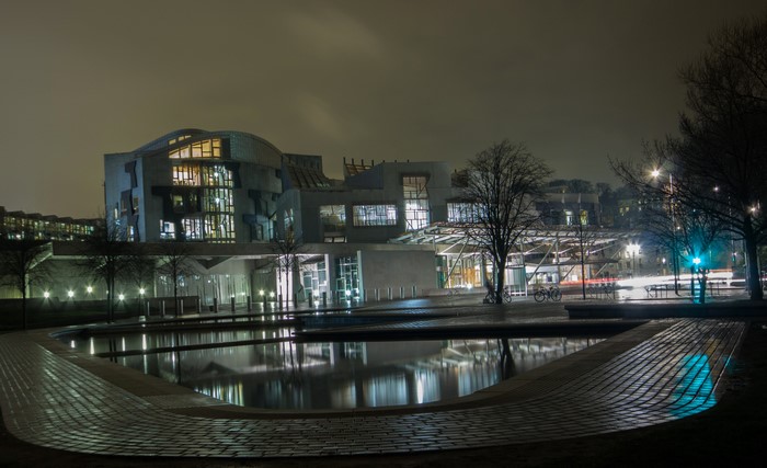 Scottish Parliament building at night with pond