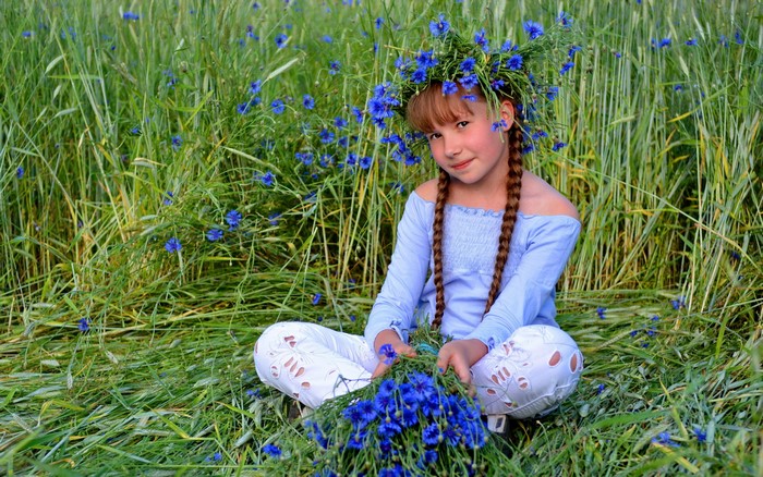 Girl with cornflower wreath and bouquet in a field