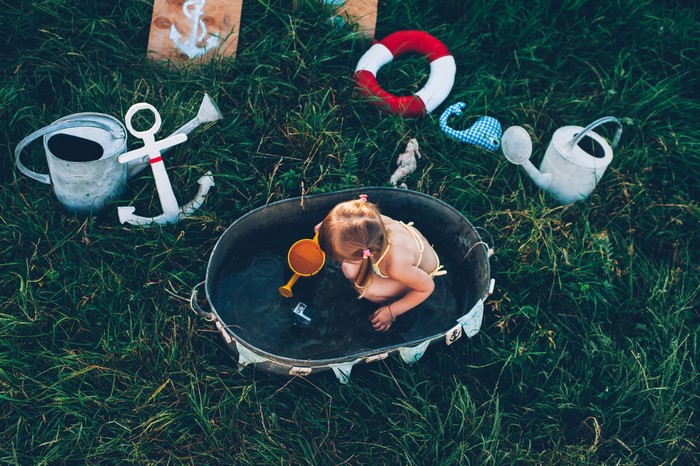 Little girl playing in a tub with nautical toys