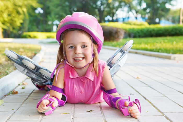 Little girl in helmet and rollerblades