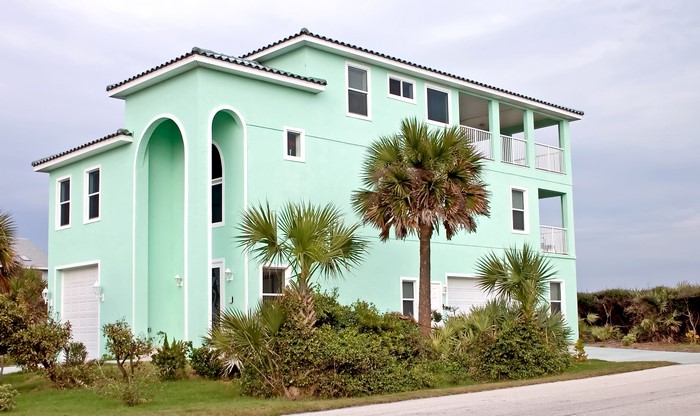 A mint green mansion with palm trees