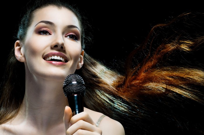 Woman singing into a microphone with hair flowing