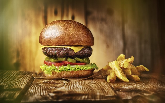 Hamburger with cheese, lettuce, tomato, pickles, and fries