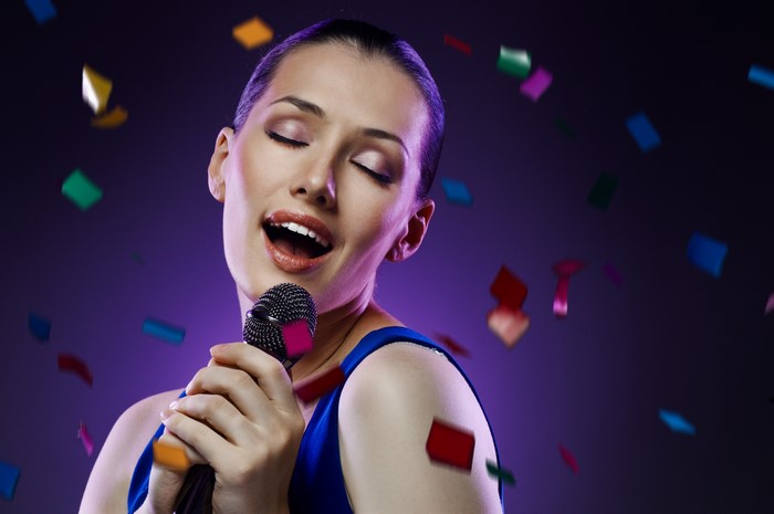 Woman singing into a microphone with confetti