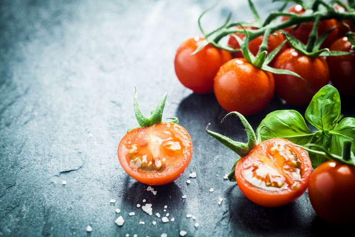 Cherry tomatoes with basil on a dark surface