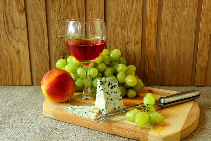 Still-life with wine, grapes, peach, blue cheese, and knife