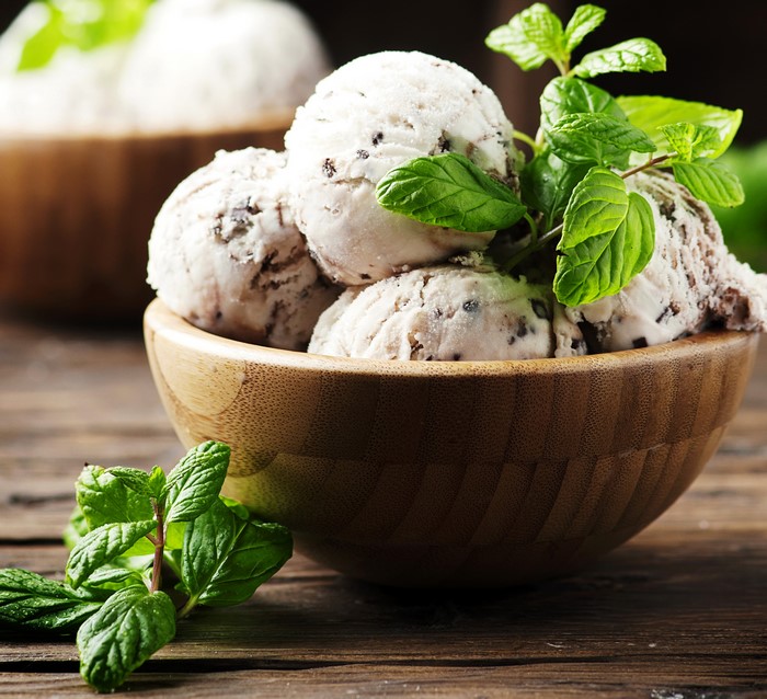 Mint chocolate chip ice cream in a wooden bowl with mint leaves