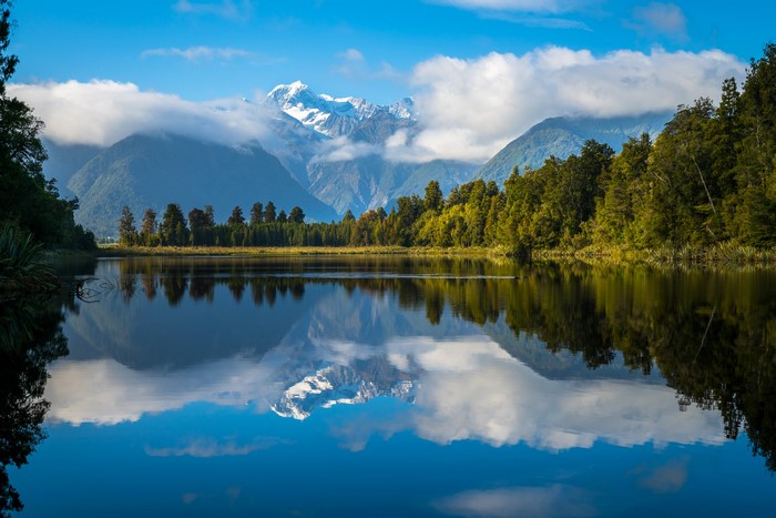 Lake Matheson with snow-capped mountains and forest reflection
