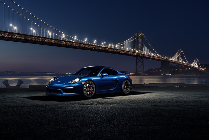Blue Porsche 911 GT4 parked by a bridge at night