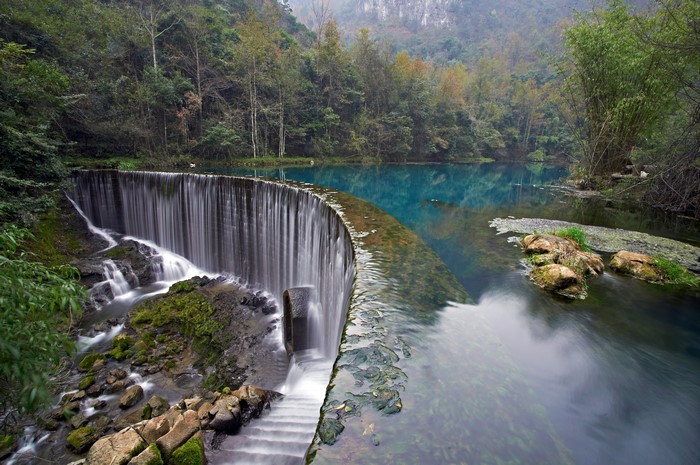 Waterfall and turquoise lake in a forest
