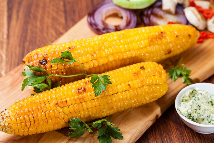 Two ears of grilled corn with parsley and butter