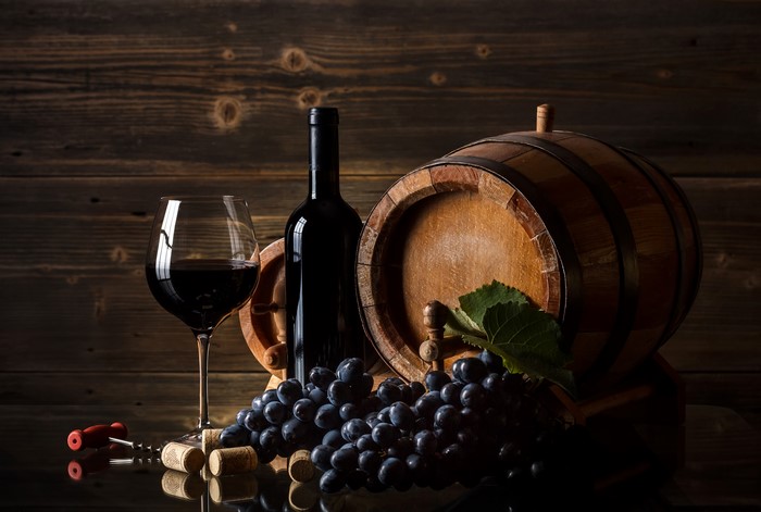 Wine bottle, glass, grapes, and barrel