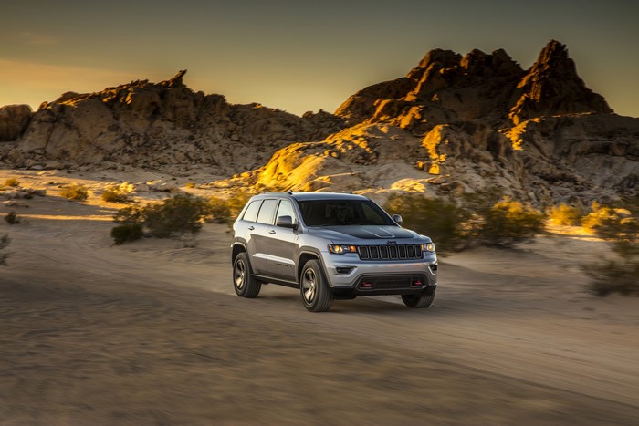 Silver Jeep Grand Cherokee driving on a dirt road in the desert