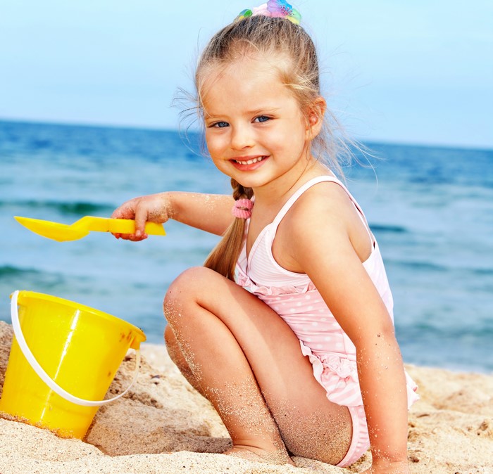 Girl playing with bucket and shovel on the beach