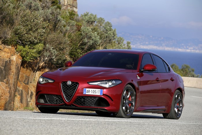 Red Alfa Romeo Giulia Quadrifoglio driving on a coastal road