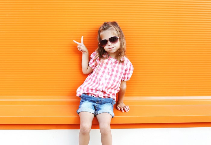 Little girl with sunglasses making peace sign