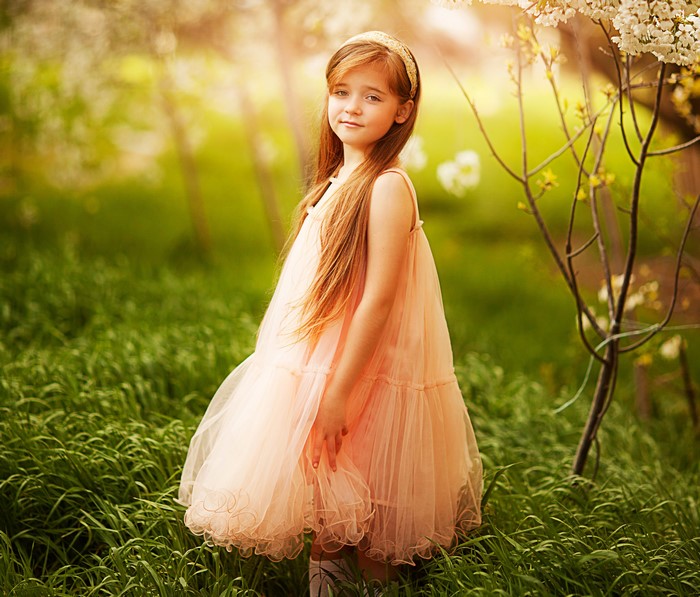 Young girl in a peach dress in a grassy field