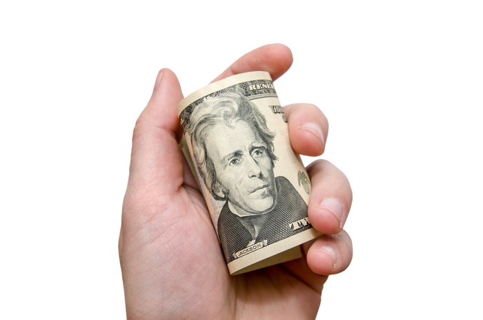 Hand holding rolled up twenty dollar bill