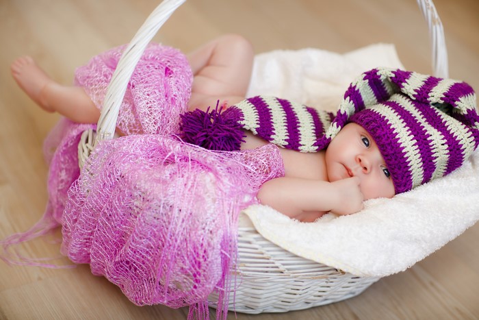 Baby in a striped winter hat in a wicker basket