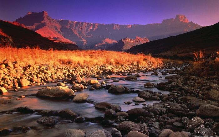 River flowing through rocky valley towards mountains at sunset