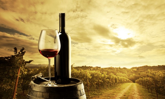 Wine bottle and glass in vineyard at sunset