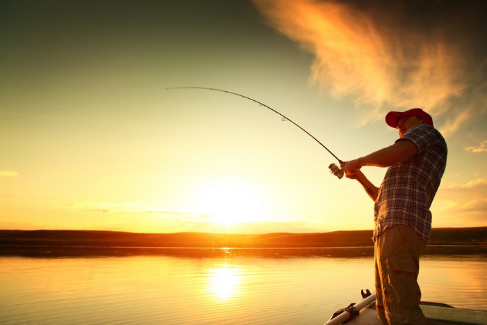 Man fishing from a boat at sunset